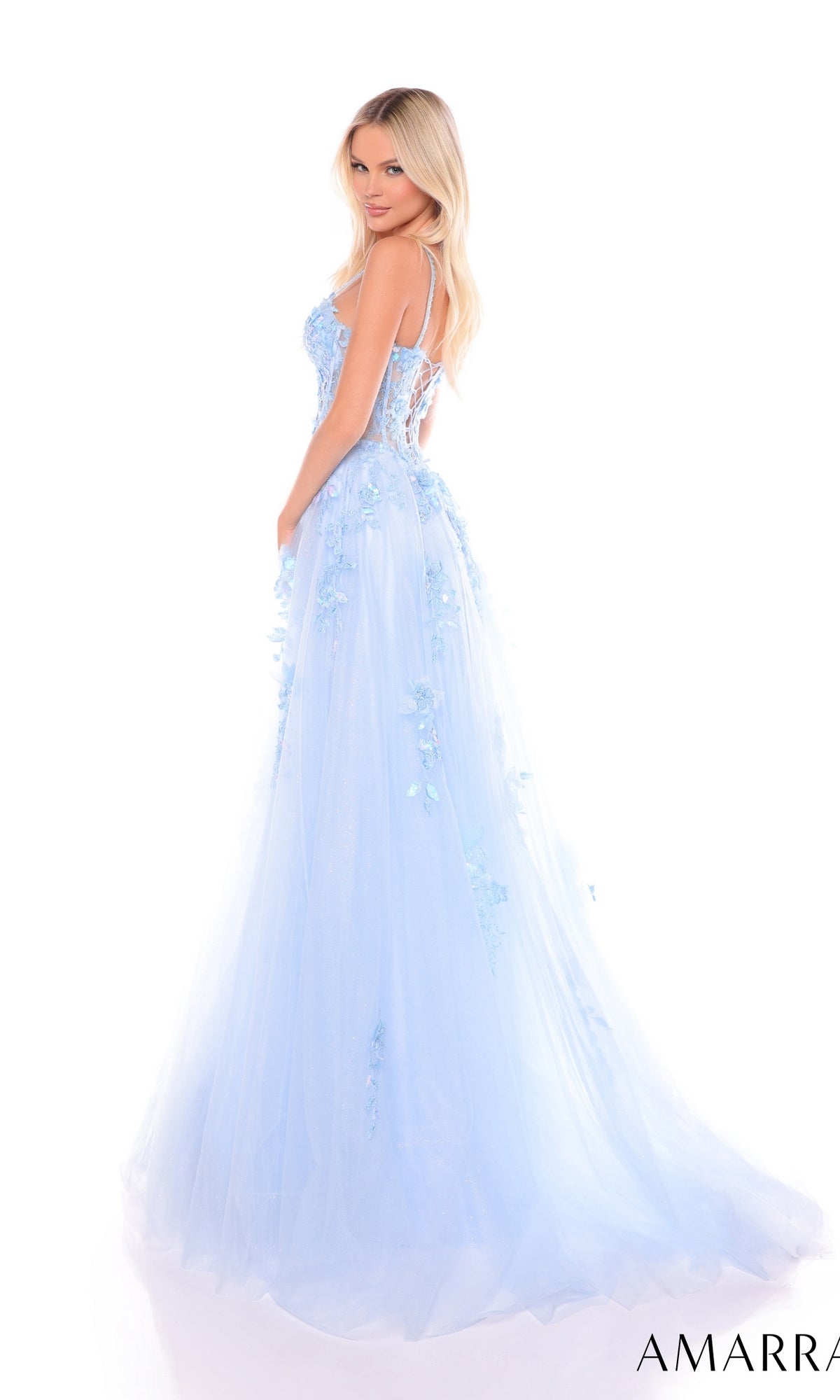 A woman with long blonde hair poses gracefully against a white background in the Amarra 88086, a light blue floor-length formal dress with floral embellishments and a sheer corset bodice, perfect for prom.